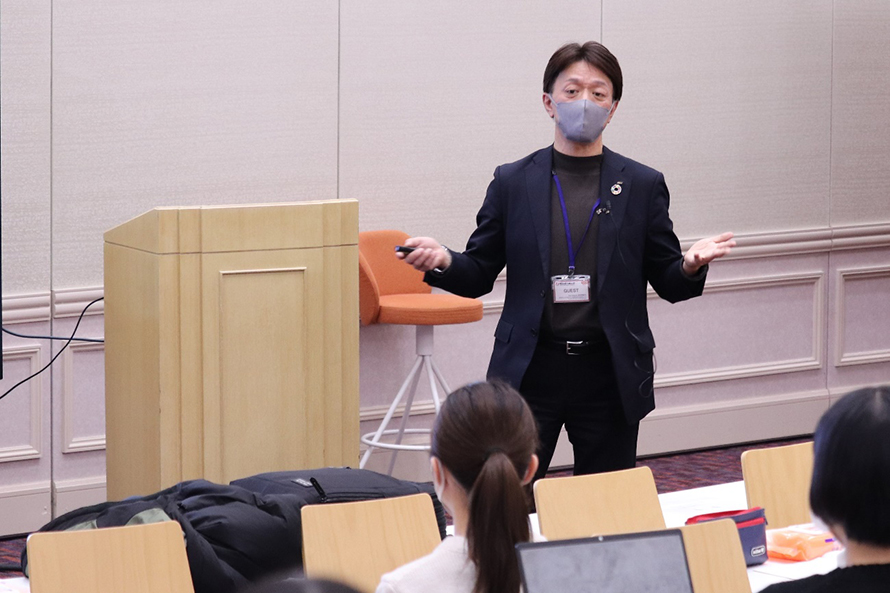 開志専門職大学のキャンパスで講演を行う藤原執行役員の写真
