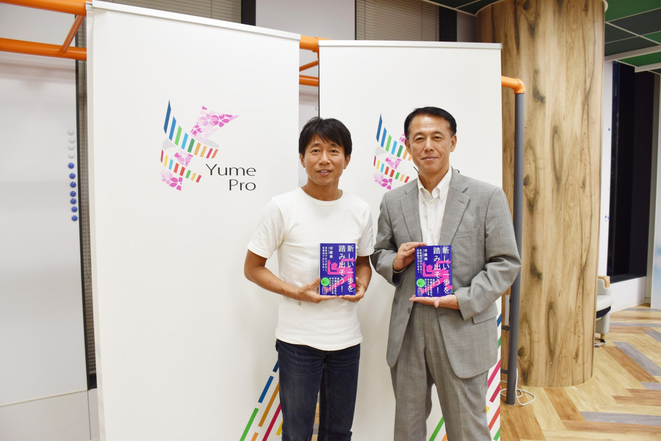 守屋さんの書籍「新しい一歩を踏み出そう」を手に 守屋氏(左)と横田CINO(右)